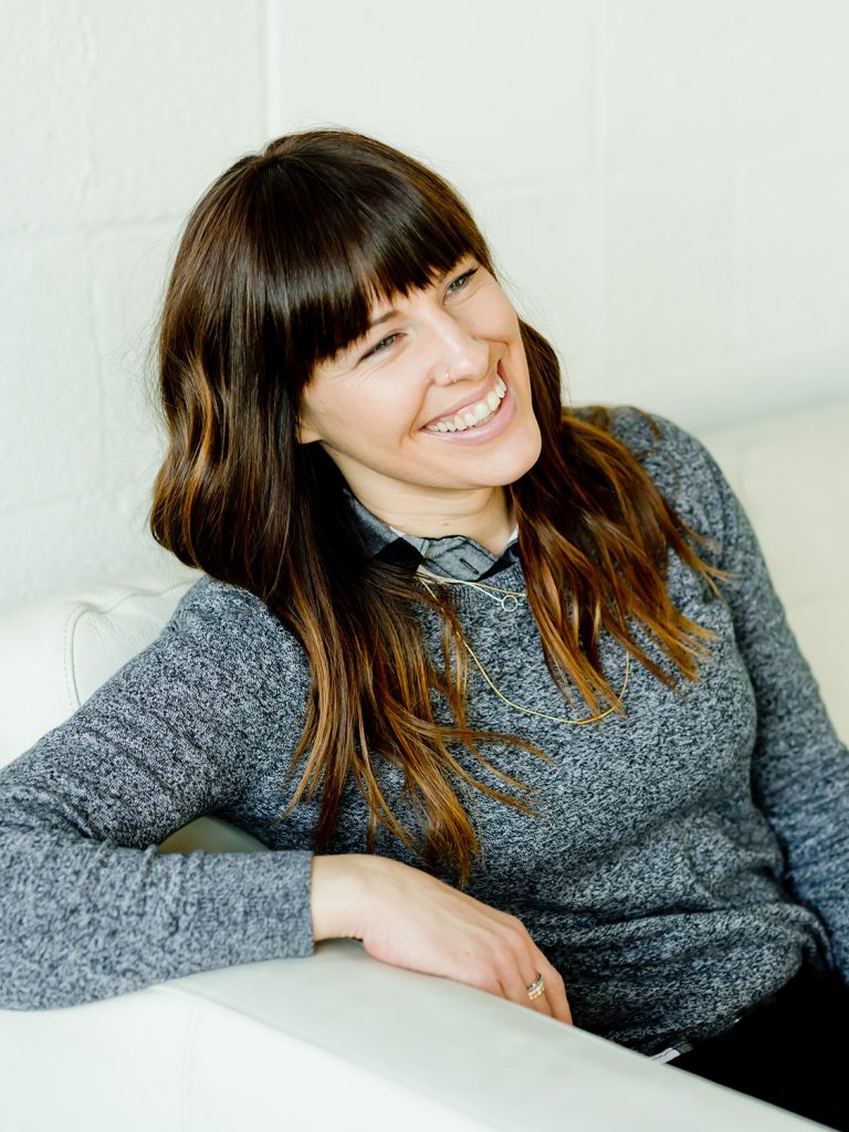 Smiling woman in a gray sweater sitting on a couch